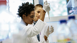 Scientists injecting a solution into a vial.